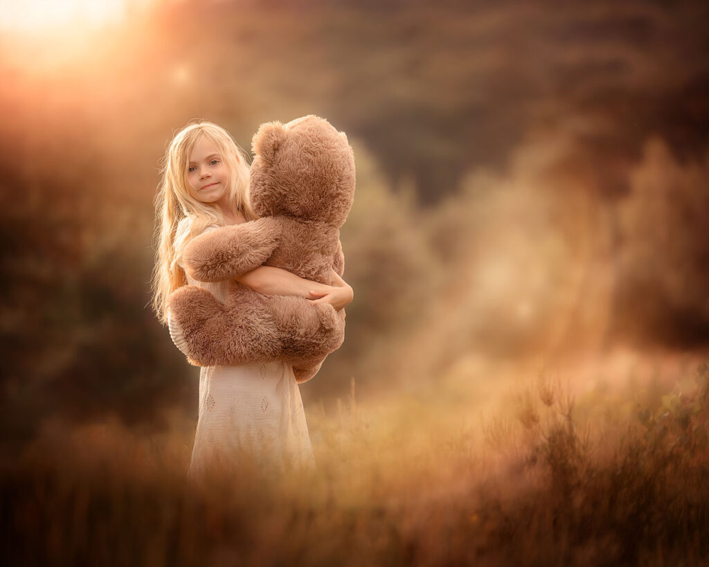 Canon Eos R6 portrait of a little blonde girl holding a teddy bear during sunset by dutch natural light photographer Willie Kers