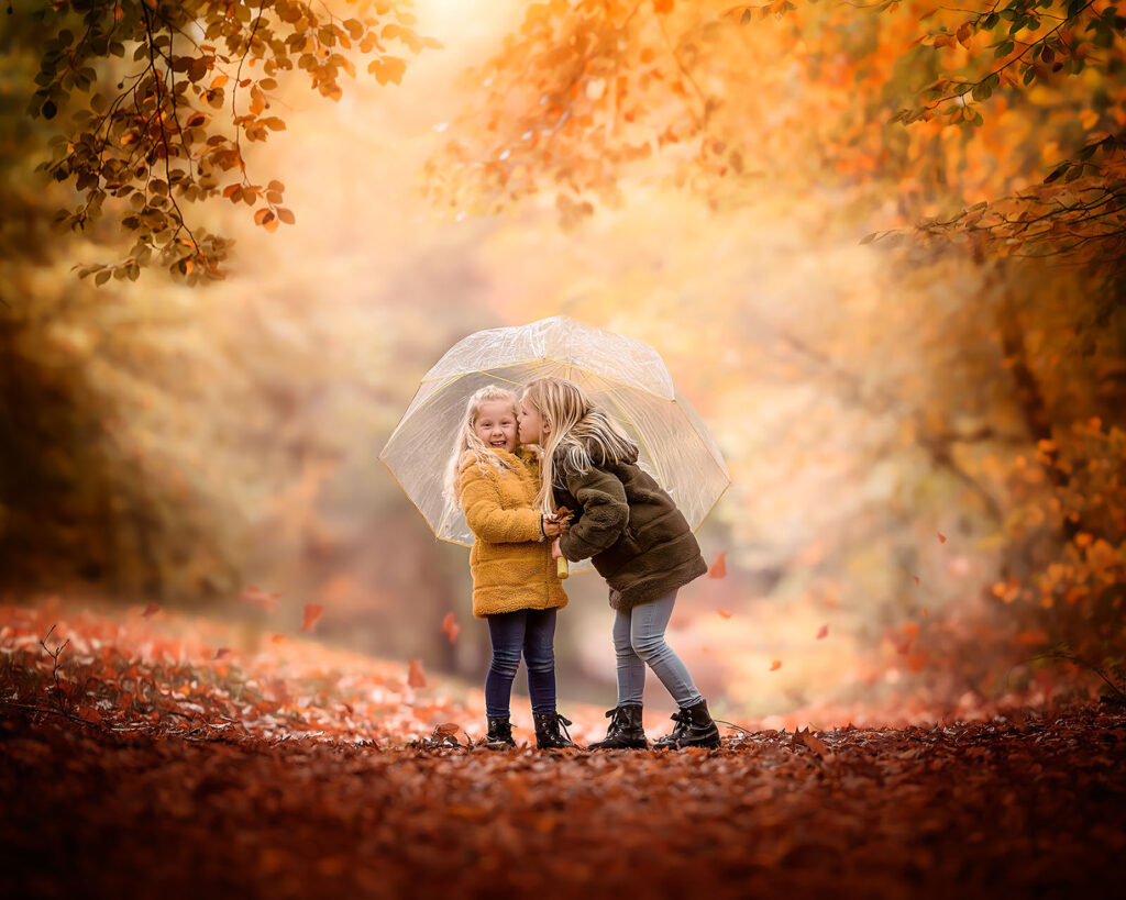 Canon EOS R fall child portrait of two sisters with an umbrella catching falling leaves by Dutch natural light photographer Willie Kers