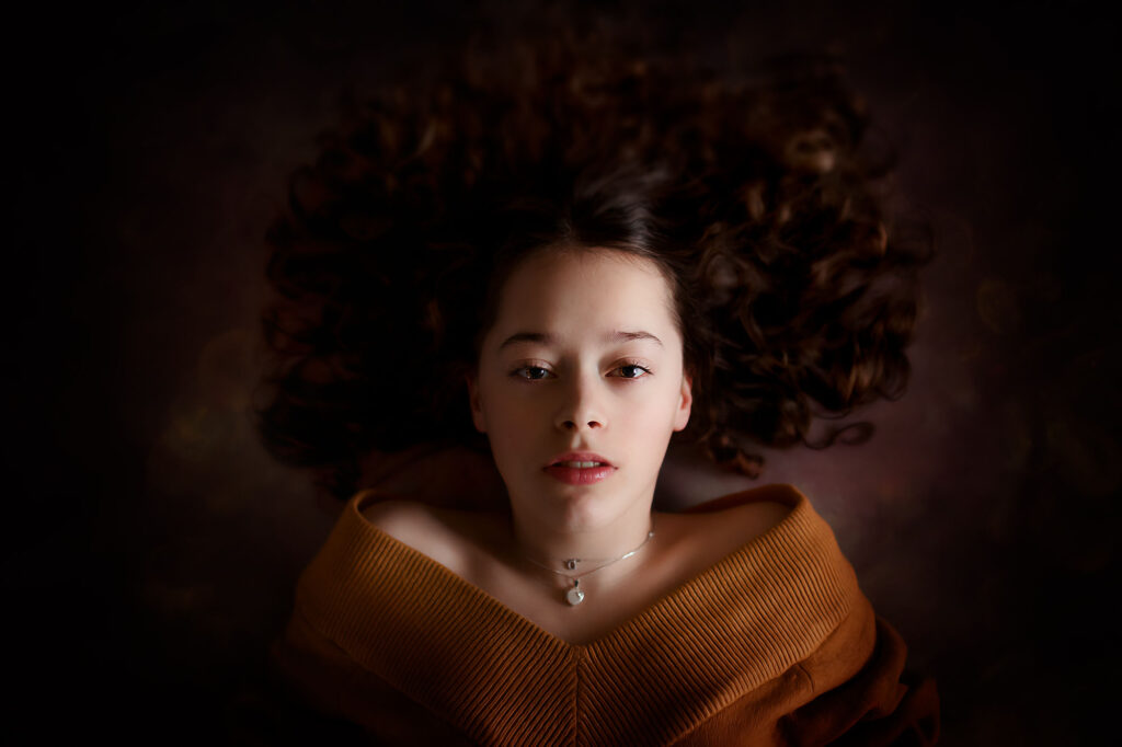 Canon EOS R6 portret van een jongen vrouw met krullen liggend op de grond in de stijl van Rembrandt van Rhijn door fotograaf Willie Kers uit Apeldoorn