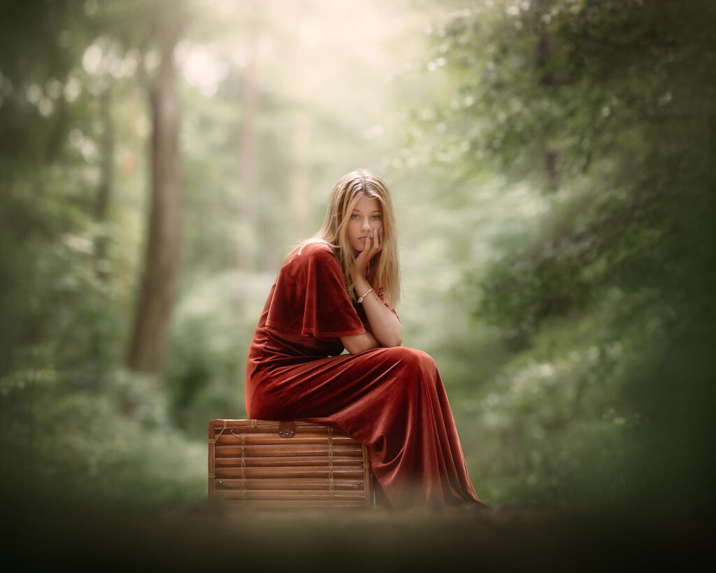 Portret van een jonge vrouw zittend op een koffer in het groene bos door natuurlijk licht fotograaf Willie Kers uit Apeldoorn
